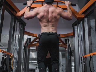 Ragazzo in palestra durante una trazione alla sbarra con presa larga